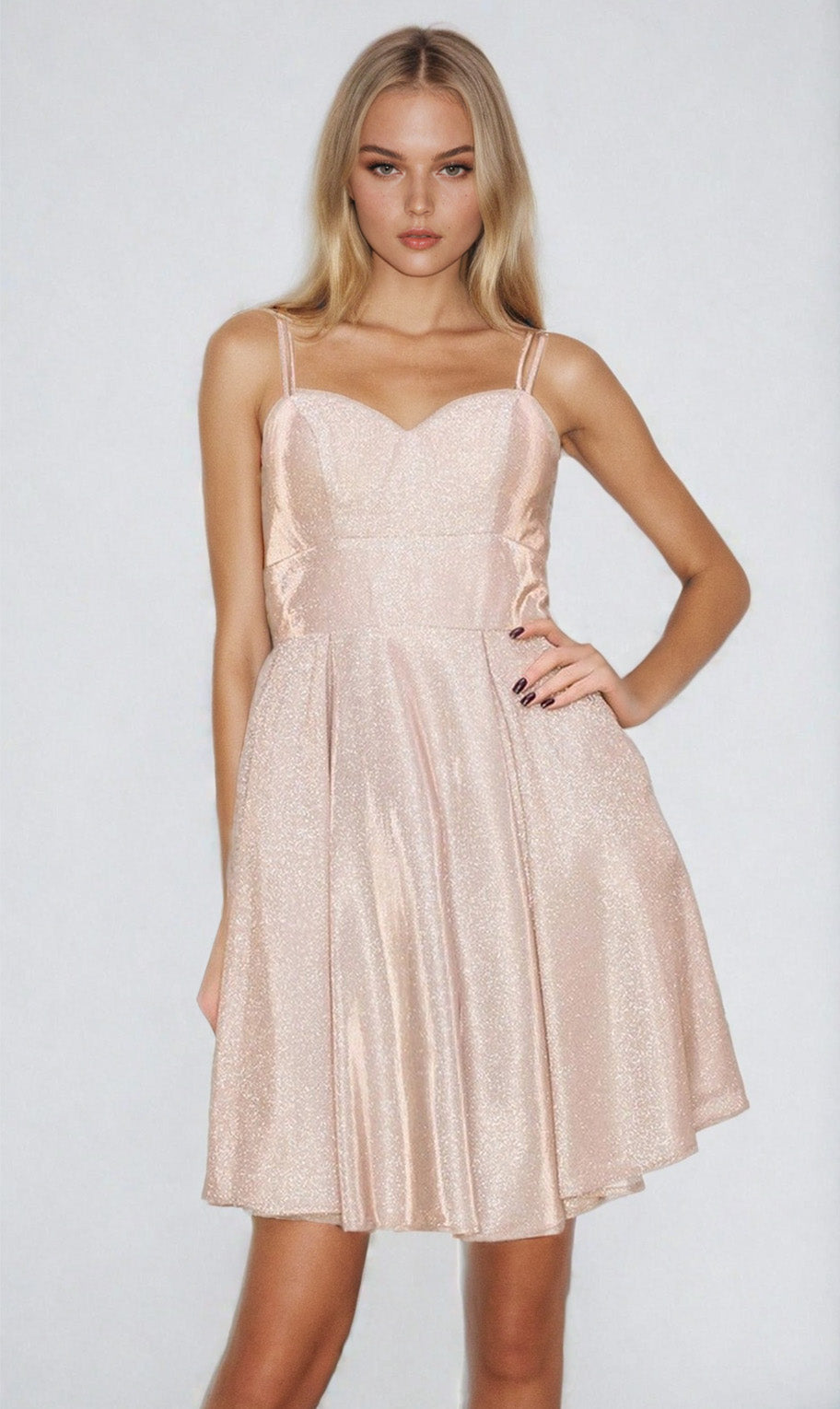 A woman wearing the Lace-Up Short Glitter A-Line Homecoming Dress 8011J, a light pink sparkly semi-formal dress with thin straps, stands against a plain light background.